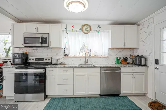 a kitchen with granite countertop a stove top oven sink and cabinets