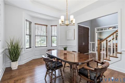 a dining room with wooden floor a chandelier a wooden table and chairs