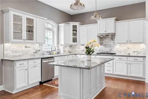 a kitchen with granite countertop a sink and white cabinets