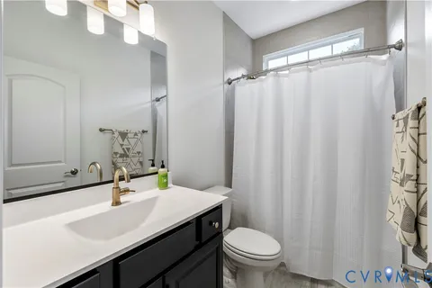 a bathroom with a sink a toilet a mirror and shower curtain