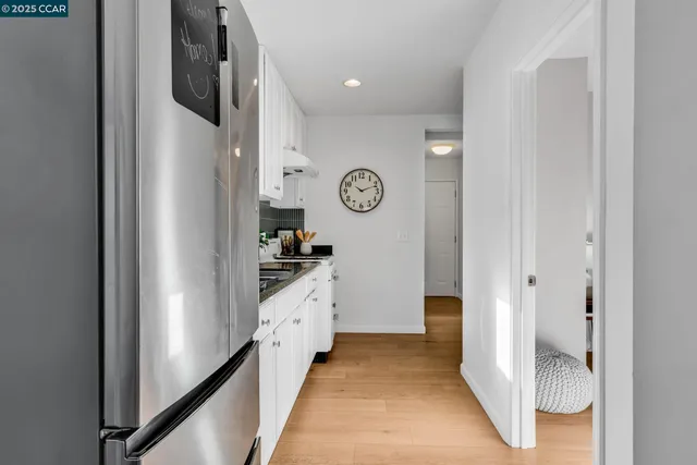 a kitchen with stainless steel appliances a refrigerator a stove a sink and a dining table with wooden floor