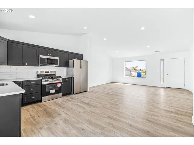 a kitchen with granite countertop a refrigerator and a stove top oven