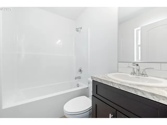 a bathroom with a granite countertop sink toilet a mirror and bathtub