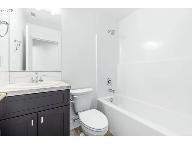 a bathroom with a granite countertop sink toilet a mirror and bathtub