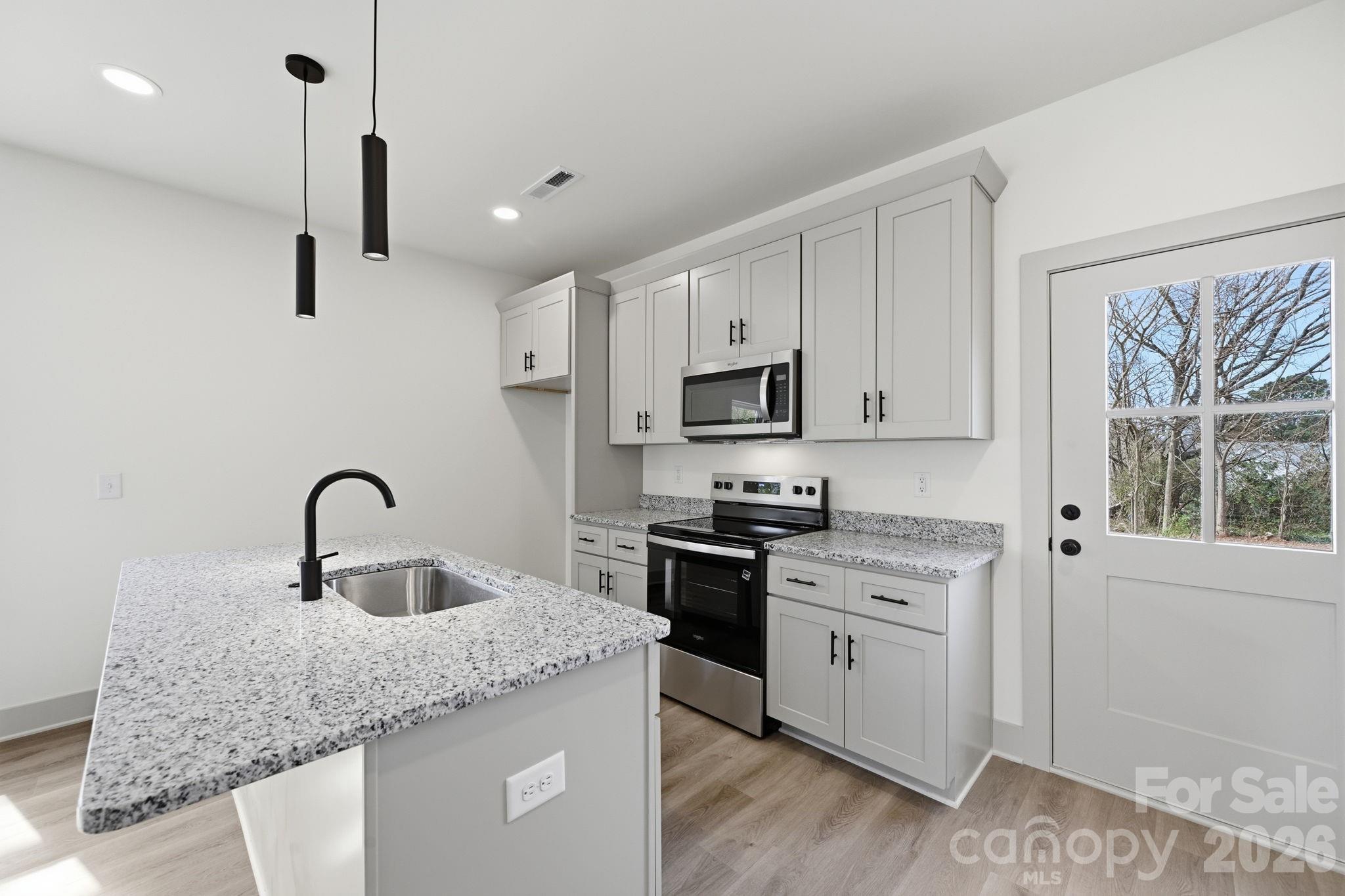 509 Beard Street Monroe, NC 28110 - Photo 13 of 33 a kitchen with stainless steel appliances granite countertop a sink a stove a window and cabinets
