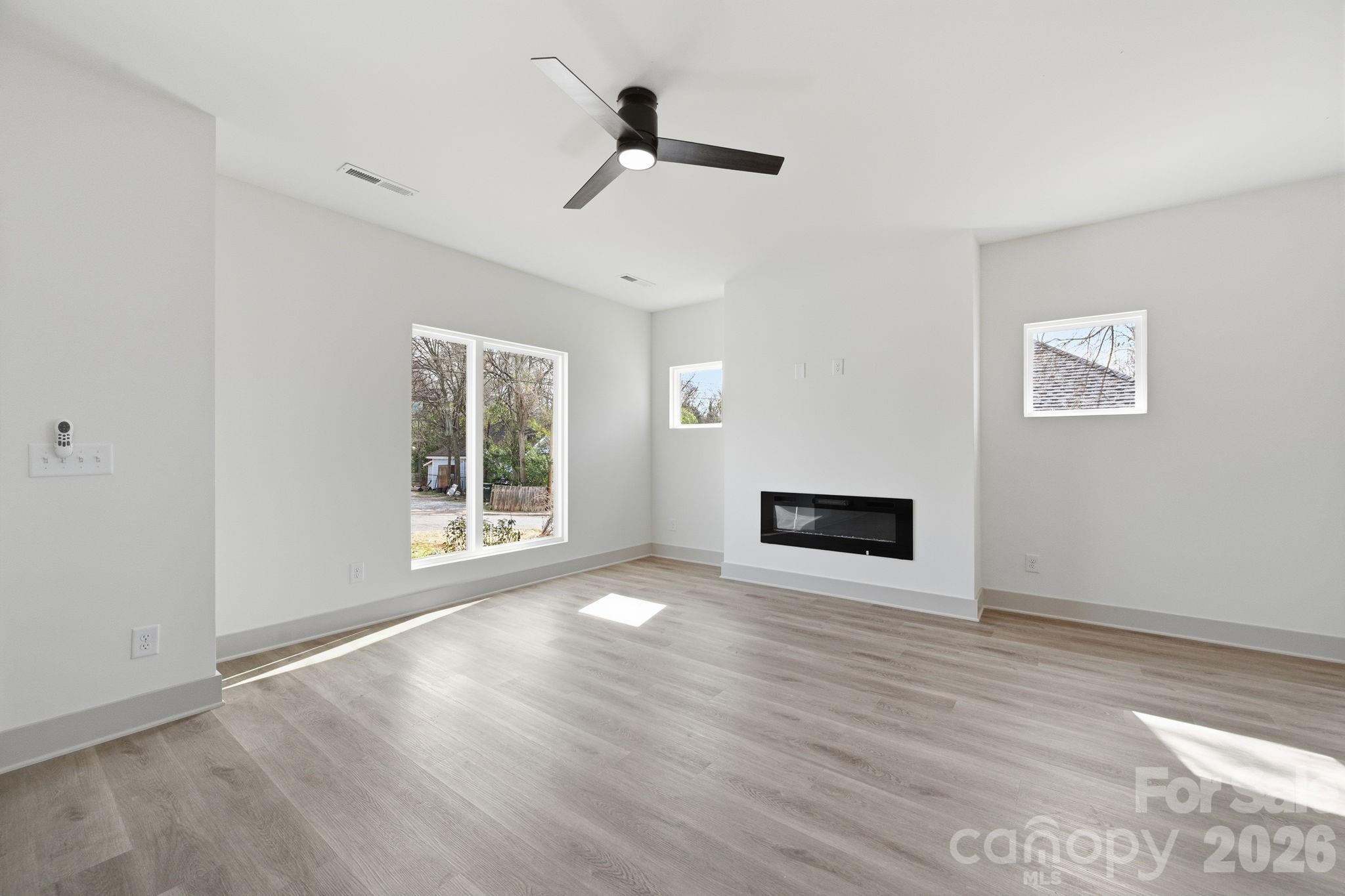 509 Beard Street Monroe, NC 28110 - Photo 8 of 33 a view of a livingroom with wooden floor a ceiling fan and windows