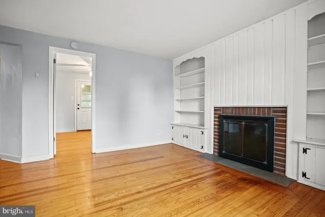 a view of empty room with wooden floor and fireplace