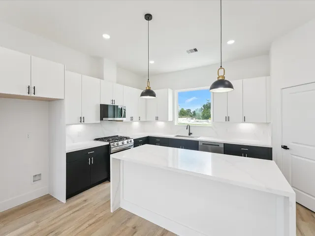 a view of a kitchen with a sink and dishwasher a refrigerator with wooden floor
