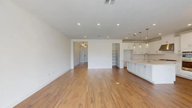 a view of kitchen with kitchen island wooden floor center island and stainless steel appliances