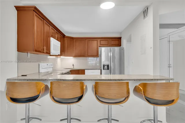 a kitchen with granite countertop a dining table chairs and a sink