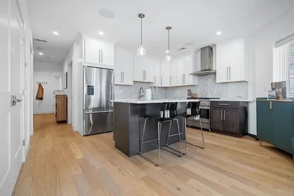 a kitchen with stainless steel appliances kitchen island granite countertop a table chairs refrigerator and microwave