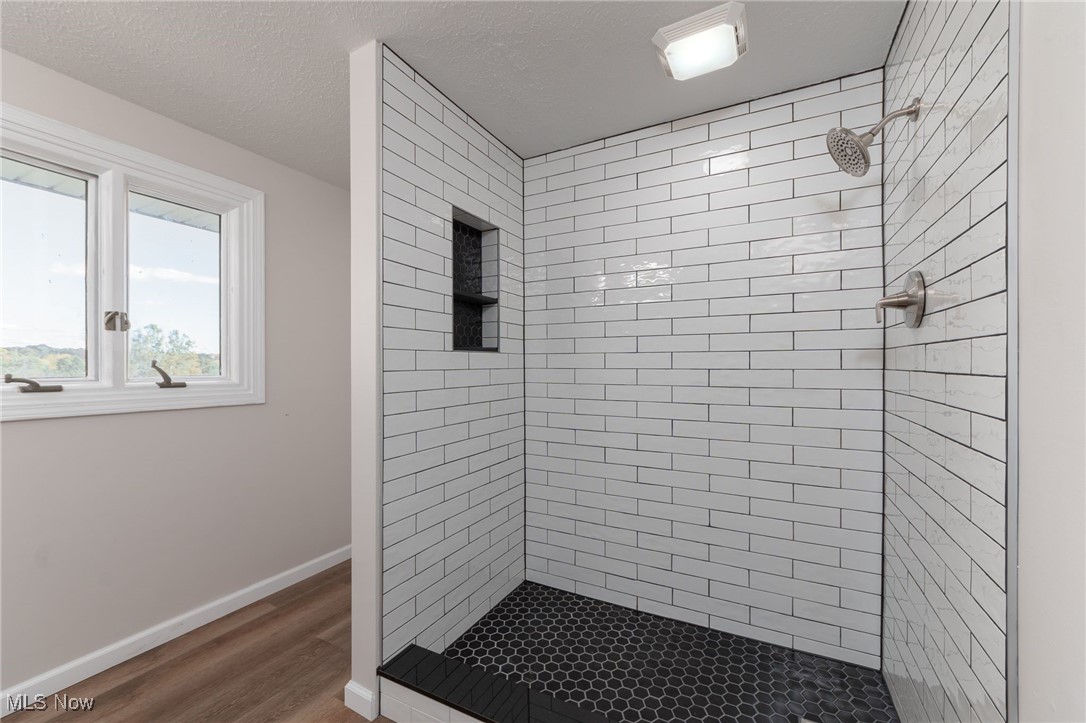 13295 Sperry Road Chesterland, OH 44026 - Photo 24 of 35 Bathroom with a textured ceiling, wood-type flooring, and tiled shower