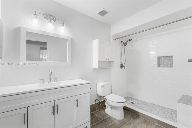 a bathroom with a toilet sink a mirror and shower