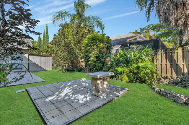 a view of a yard with plants and a large tree