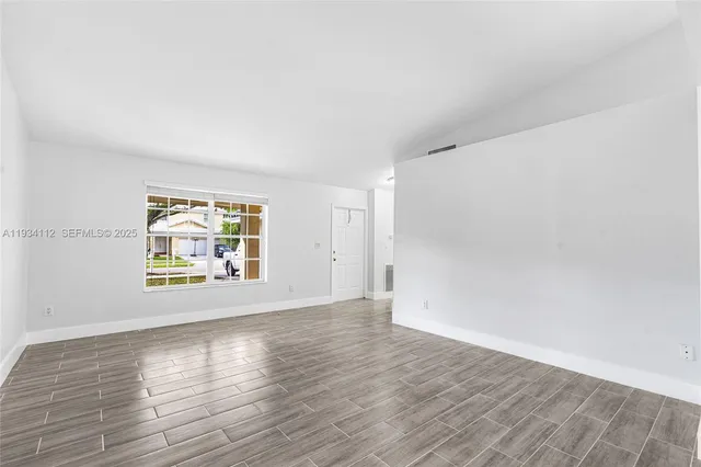 an empty room with wooden floor and window