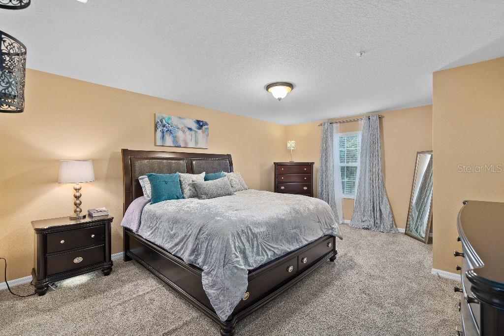 2417 Passamonte Drive, Unit 1E Winter Park, FL 32792 - Photo 7 of 15 a bedroom with a bed a couch and a flat tv screen on the dresser