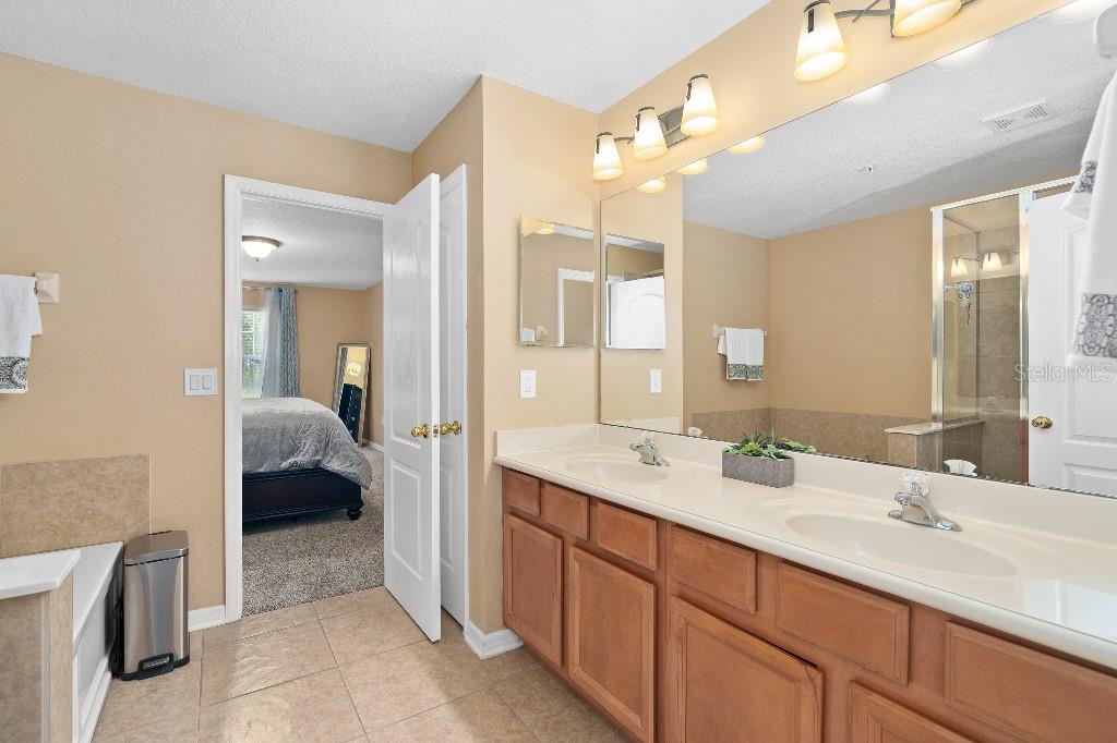 2417 Passamonte Drive, Unit 1E Winter Park, FL 32792 - Photo 9 of 15 a en suite bathroom with a double vanity sink a mirror and a shower