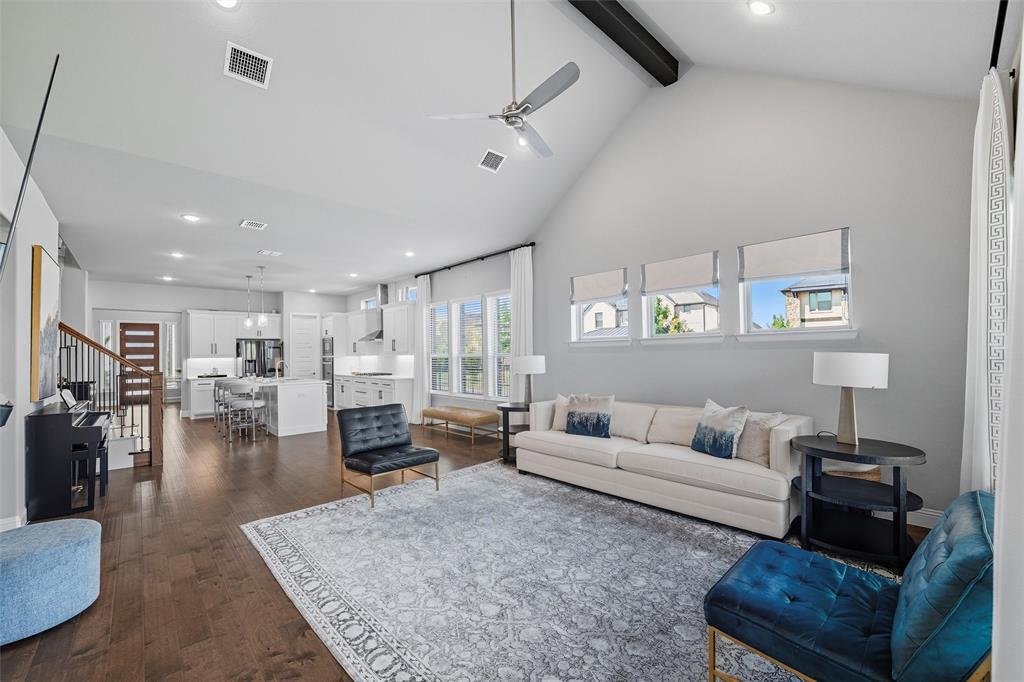 8492 Chapote Road Frisco, TX 75035 - Photo 12 of 40 Living Area features vaulted ceiling with exposed beam and ceiling fan. Decorative fireplace as the focal point. Open layout providing ample space for seating arrangements. Wide-plank hardwood flooring extending through the space.