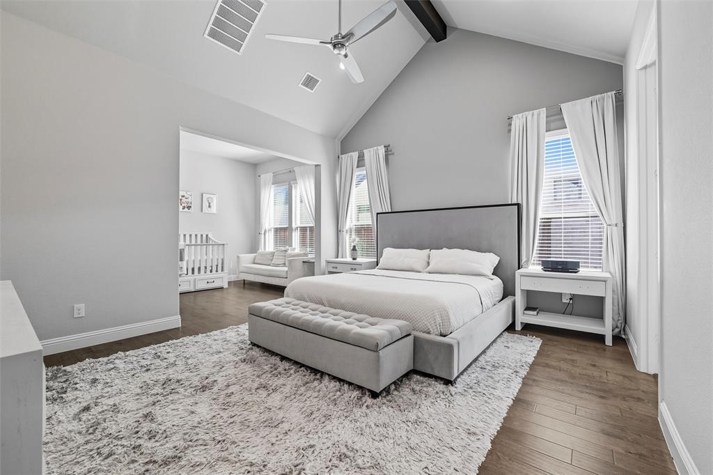 8492 Chapote Road Frisco, TX 75035 - Photo 16 of 40 Primary Bedroom features vaulted ceiling with exposed beam and ceiling fan. Spacious layout with open entry to a sitting area. Wide-plank hardwood flooring extending through the space.