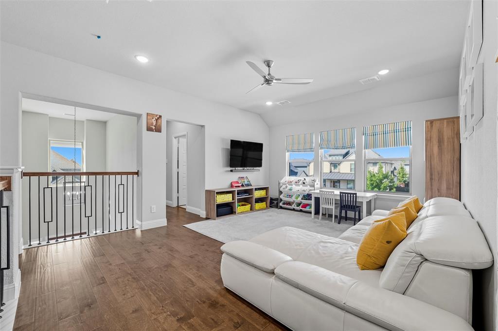 8492 Chapote Road Frisco, TX 75035 - Photo 23 of 40 Loft features vaulted ceiling with ceiling fan and recessed lighting. Open railing with wood handrail and wrought iron balusters overlooking the stairway. Wide-plank hardwood flooring extending through the space.
