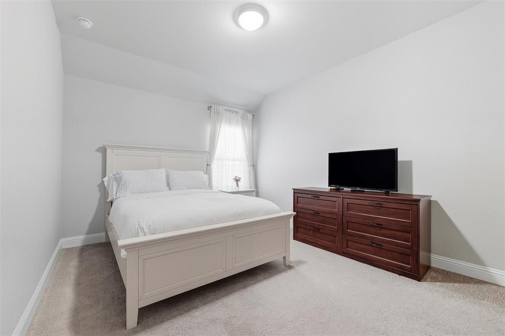 8492 Chapote Road Frisco, TX 75035 - Photo 26 of 40 Secondary Bedroom features vaulted ceiling with flush-mount light. Spacious layout with soft carpet flooring extending through the space.