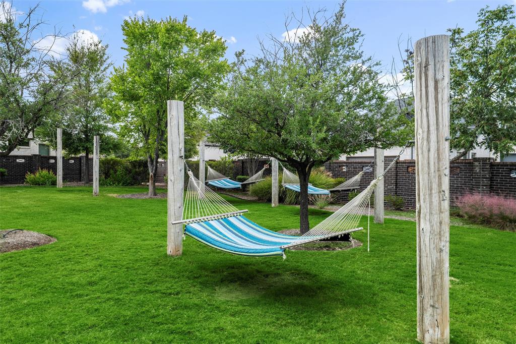 8492 Chapote Road Frisco, TX 75035 - Photo 33 of 40 Community Hammock Park features multiple striped hammocks suspended between wooden posts under shaded trees. Expansive green lawn extending through the area.