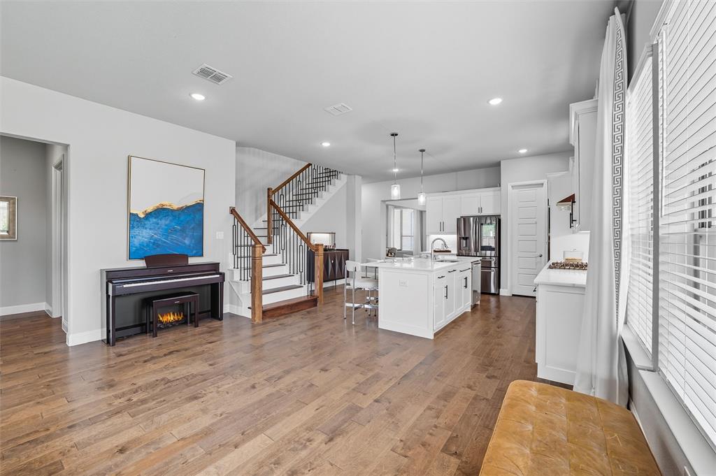 8492 Chapote Road Frisco, TX 75035 - Photo 10 of 40 Staircase Area features recessed lighting above an open stairway with wood handrails and wrought iron balusters. Open layout adjacent to the kitchen island with pendant lights and stainless steel appliances. Wide-plank hardwood flooring extending through the space.