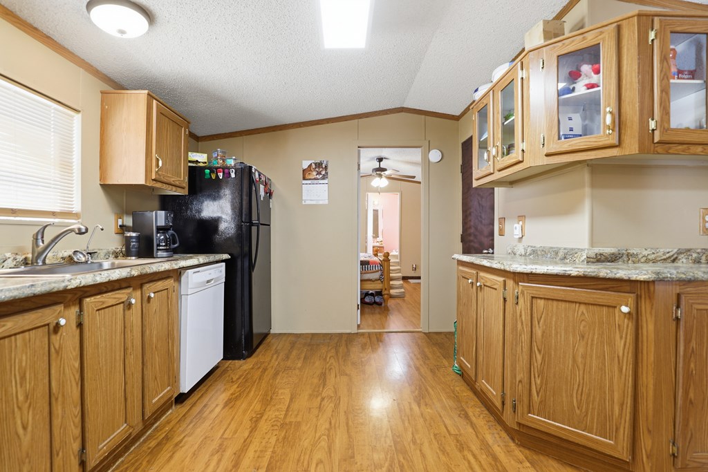 912 Alamo Road Fredericksburg, TX 78624 - Photo 6 of 21 a kitchen with stainless steel appliances granite countertop a refrigerator a sink dishwasher and wooden cabinets with wooden floor