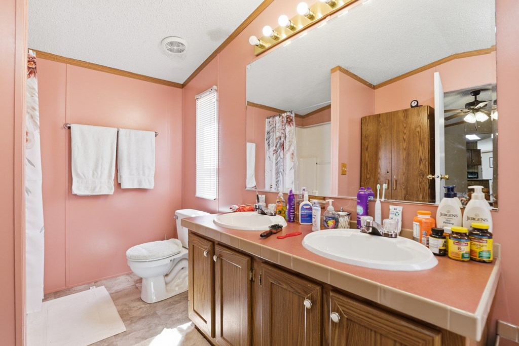 912 Alamo Road Fredericksburg, TX 78624 - Photo 9 of 21 a bathroom with a granite countertop sink a toilet a mirror and shower