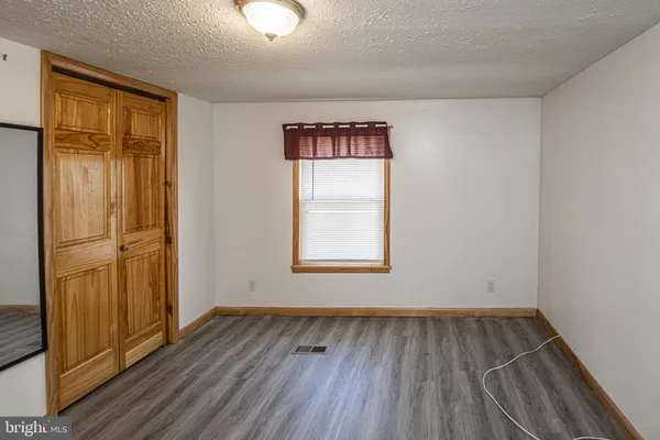an empty room with wooden floor cabinet and windows