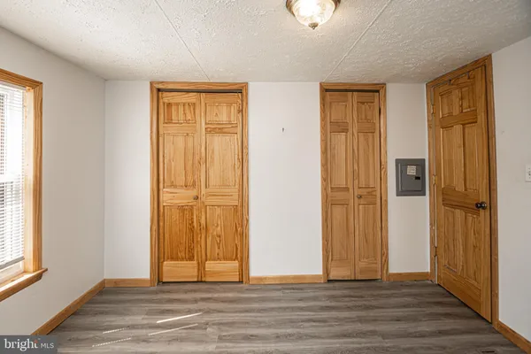 an empty room with wooden floor mirror and windows