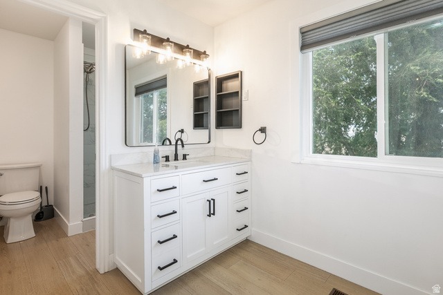 11906 Woodridge Road Sandy, UT 84094 - Photo 17 of 35 Modern primary suite bathroom featuring a white vanity with a light-toned countertop, black hardware, a rectangular mirror, and a contemporary light fixture