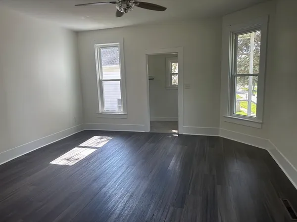 a view of an empty room with wooden floor and a window