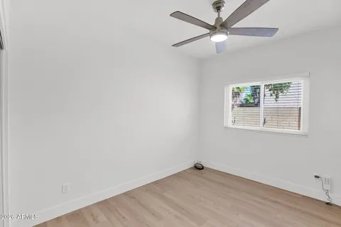 an empty room with wooden floor ceiling fan and windows