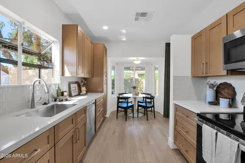 a kitchen with stainless steel appliances granite countertop a sink stove refrigerator and cabinets