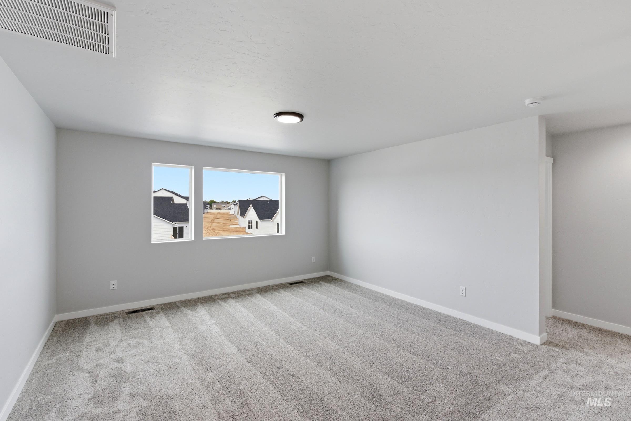 16558 Dunning Way Caldwell, ID 83607 - Photo 17 of 35 Spacious room featuring light gray carpet flooring, white baseboards, and two large windows providing natural light