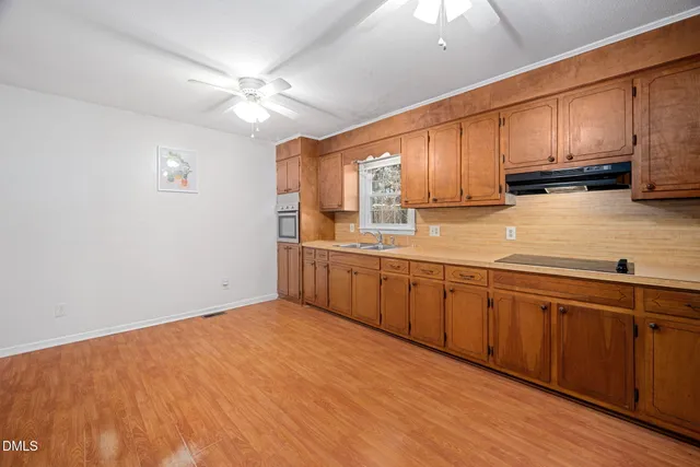 a kitchen with stainless steel appliances granite countertop a sink cabinets and wooden floor