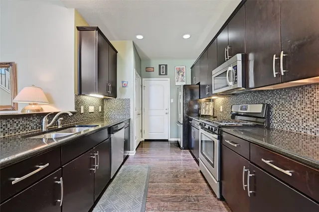a large kitchen with stainless steel appliances granite countertop a stove a sink dishwasher and a refrigerator