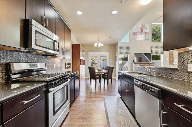 a kitchen with stainless steel appliances granite countertop a stove a sink and a microwave