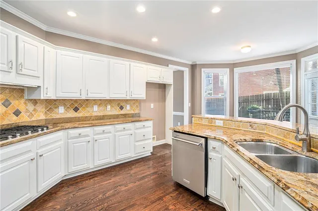 a kitchen with granite countertop a sink and white cabinets with wooden floors