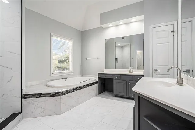 a bathroom with a granite countertop sink a bathtub a mirror and vanity