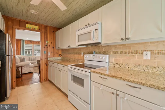 a kitchen with stainless steel appliances granite countertop a stove a sink and white cabinets