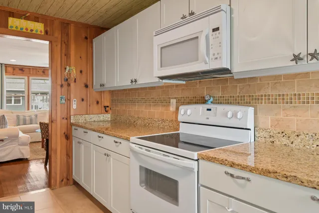 a kitchen with granite countertop white cabinets and white appliances