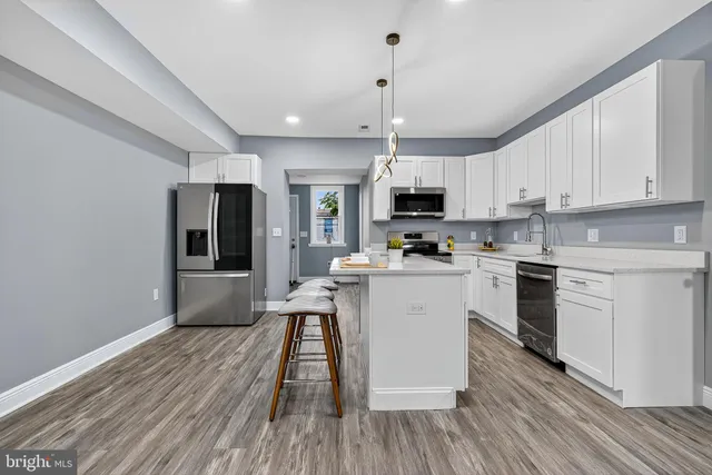 a kitchen with white cabinets stainless steel appliances a sink and a refrigerator