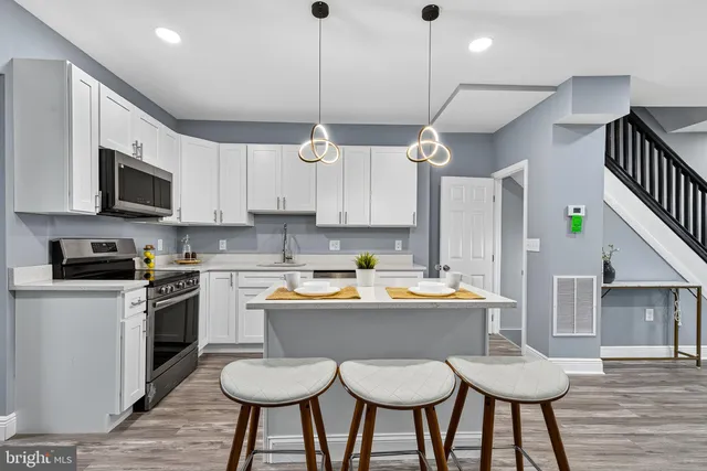 a kitchen with stainless steel appliances granite countertop a sink a stove a refrigerator cabinets and chairs