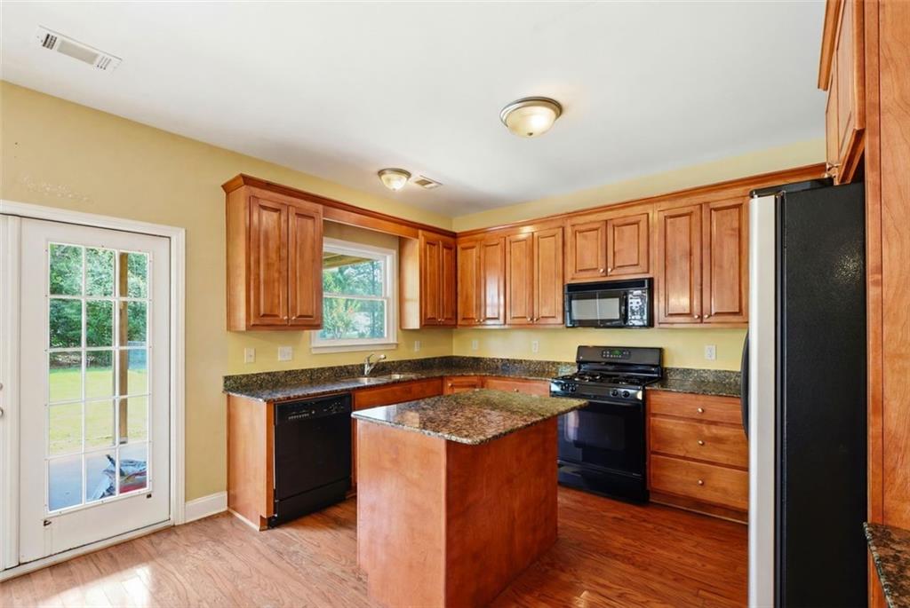 3420 Bulloch Lake Road Loganville, GA 30052 - Photo 22 of 57 a kitchen with stainless steel appliances granite countertop a stove top oven a sink dishwasher a refrigerator and a microwave with wooden floor