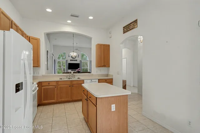 a large kitchen with a sink and dishwasher a refrigerator with wooden cabinets