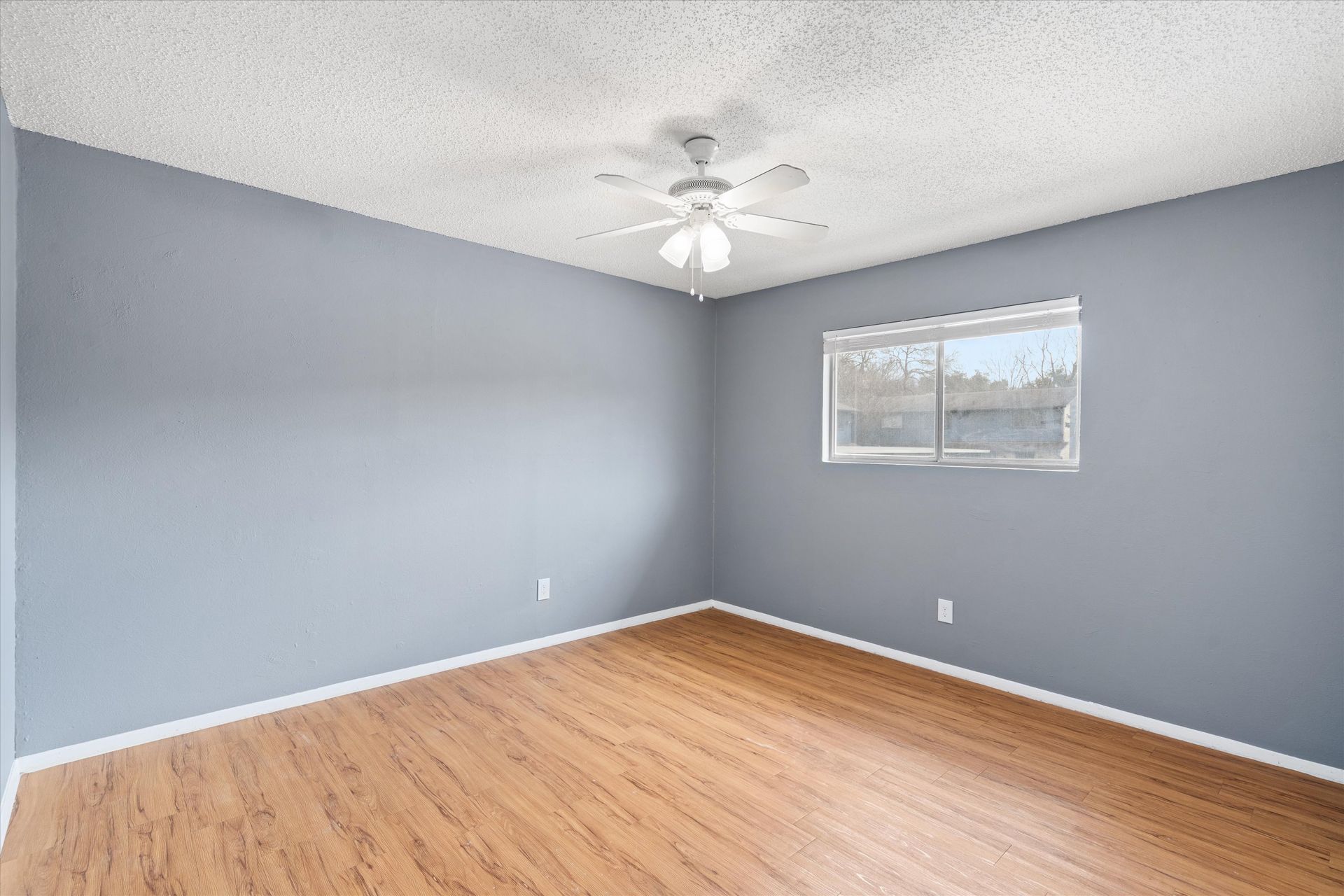 3415 Menchaca Road, Unit 114 Austin, TX 78704 - Photo 8 of 14 Unfurnished room with a textured ceiling, wood finished floors, baseboards, and ceiling fan