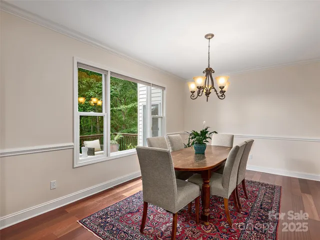 a dining room with wooden floor a chandelier a wooden table and chairs