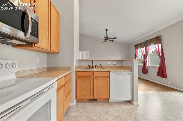 11927 Rodez Grove Peyton, CO 80831 - Photo 14 of 34 Kitchen with white appliances, visible vents, a peninsula, light countertops, and a sink